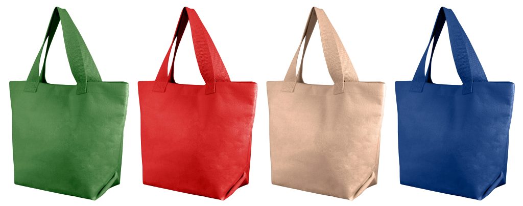 Quatre sacs cabas réutilisables en tissu non tissé vert, rouge, beige et bleu sur fond blanc
